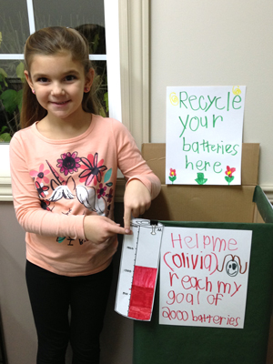 Olivia poses with her battery recycling container she made for the Ontario Schools Battery Recycling Challenge